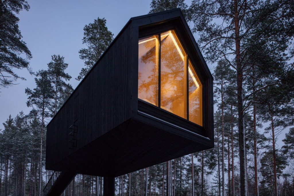 Due vedute del cottage di Studio Puisto: la facciate rivolta verso la foresta e l'ingresso tramite la scala.