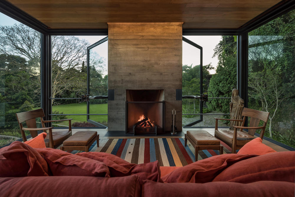 Il cuore del living, con il camino acceso e la vista sul, verde del paesaggio intorno. Rio House, in Brasile, progetto di Olson Kundig. Ph, Maíra Acayaba.